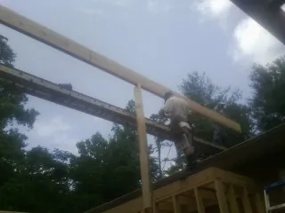 Carpenter setting a ridge beam over a new addition frame — Ice Dam Removal by Roofing Brothers in Farmingdale