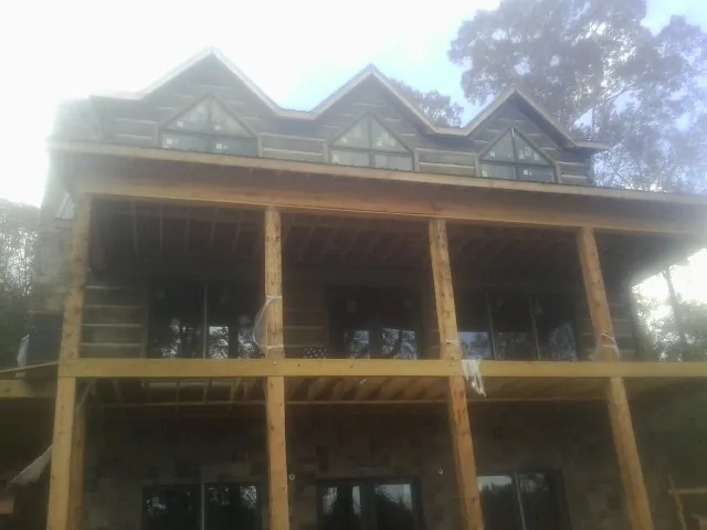 Dormers and porch framing on a large log home under construction — Roof Coating work by our crew in Farmingdale