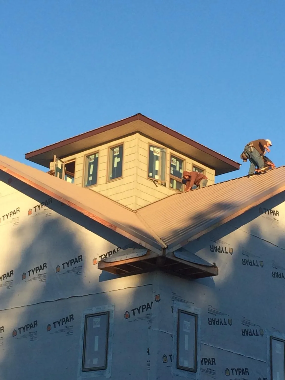 Roofers working around a rooftop cupola on a new metal roof at sunset — Roof Waterproofing in Farmingdale by Roofing Brothers